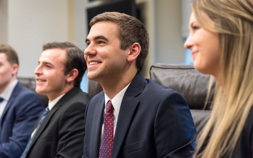 Pitt Business students smiling at a conference room table